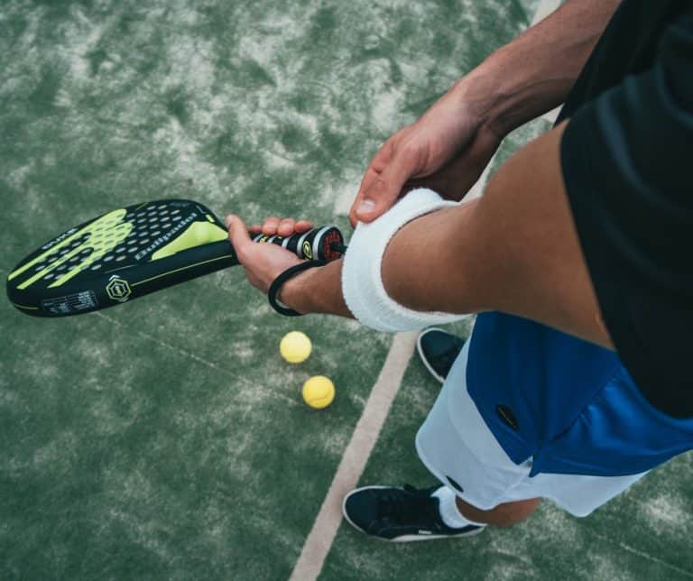 Sportowiec trzyma się za bolący łokieć na korcie