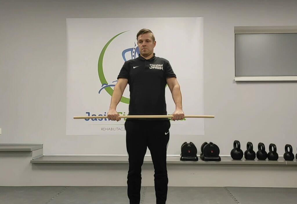 Mężczyzna z kijem podczas ćwiczeń rehabilitacyjnych.