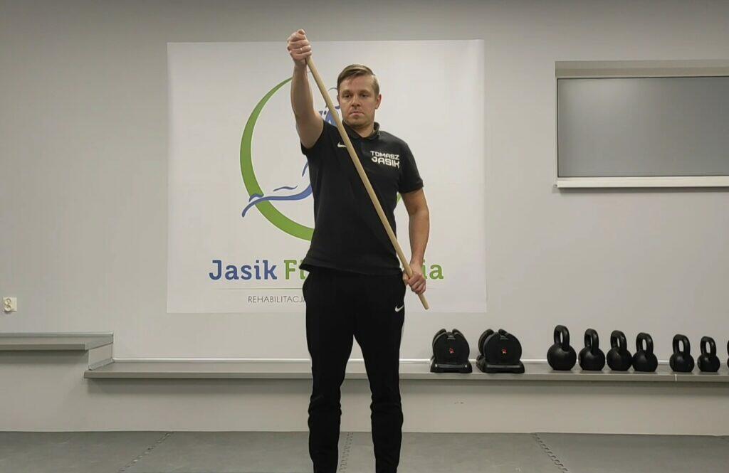Ćwiczenie z kijem w sali rehabilitacyjnej.